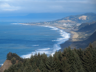 [Close-up of portion of land jutting into the ocean from the prior photo. More land(beach) is visible as are white dots of individual buildings.]